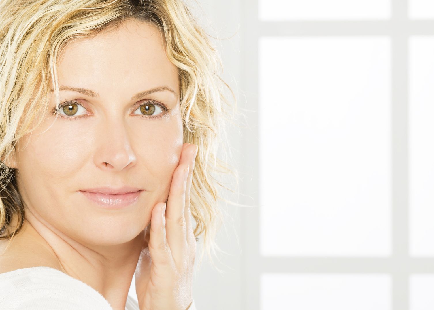 A blonde woman touching the side of her face